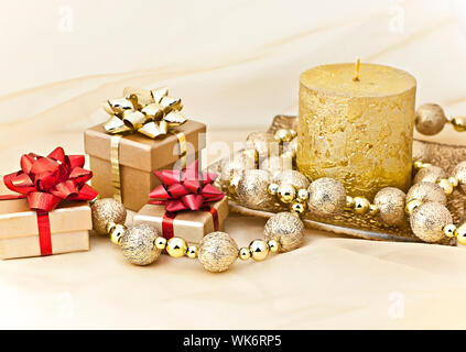 The gold background with a Christmas candle ball chains and gift boxes. Stock Photo