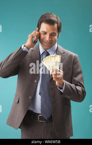 Businessman talking on mobile phone and holding Indian banknotes Stock Photo