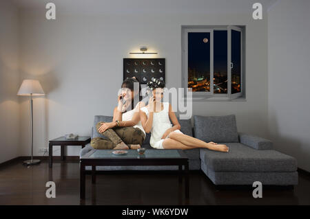 Two friends sitting on floor back to back and talking on mobile phones Stock Photo