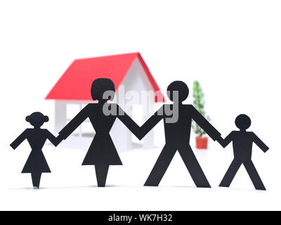 A paper family is holding hands beside their new paper house. Stock Photo