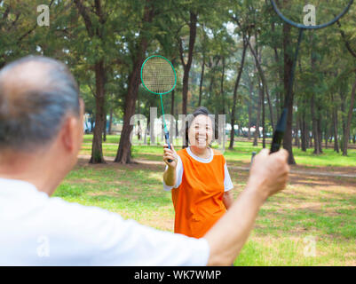 senior couple or friends playing badminton in the park Stock Photo