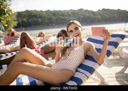 Woman wearing sunglasses smiling broadly making selfie Stock Photo