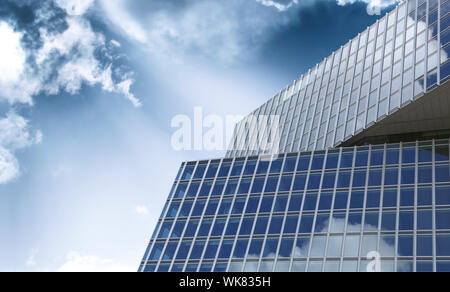 Modern office building detail with glass surface against blue sky and clouds. Office closed work from home coronavirus crisis. Stock Photo