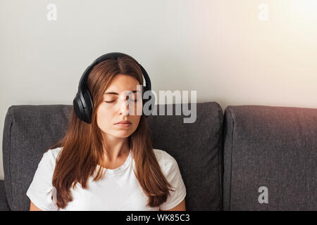 Young woman in big headphones listening to calm music or meditating Stock Photo