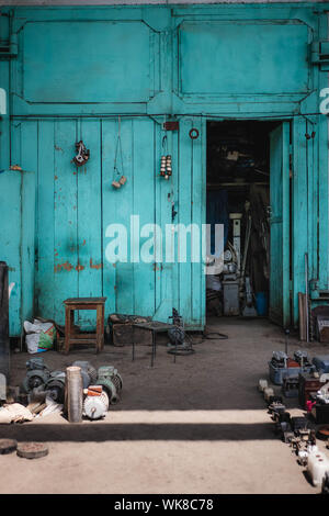 Colourful workshop entrance or shopfront with various parts and tools lying around on the ground. Stock Photo