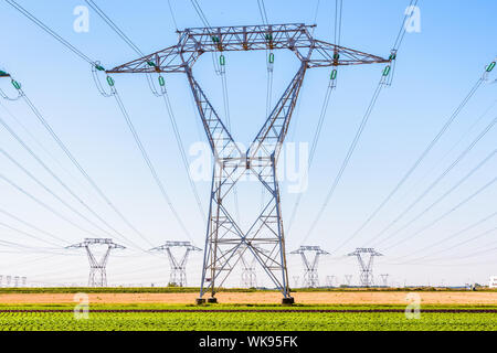 Front view of an electricity pylon in the french countryside with dozens of other pylons in the distance under a clear blue sky. Stock Photo
