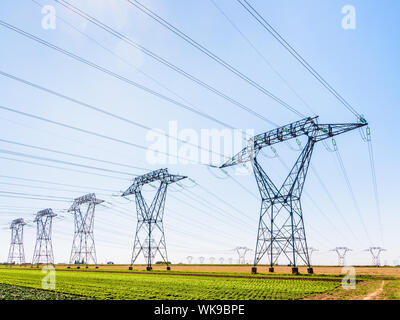 Dozens of electricity pylons in the french countryside under a clear blue sky. Stock Photo
