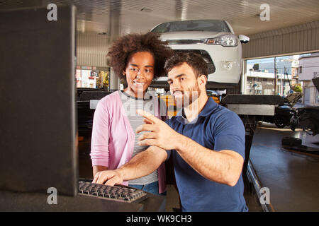 Car mechatronics technician explains on the computer the car diagnostic check at inspection Stock Photo