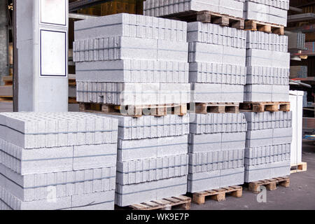 Cement building blocks stacked on pallets used for transportation and distribution at a hardware depot, warehouse or on a construction site Stock Photo