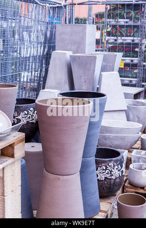 Glazed and unglazed ceramic flower pots in a variety of sizes and colors stacked on wooden pallets outside a pottery, warehouse or commercial store Stock Photo