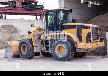 Front end loader with its bucket or scoop down parked in front of a warehouse on paving Stock Photo