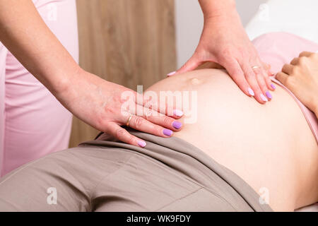 Close-up shot of obstetrician gynecologist manually examines pregnant woman's belly performing prenatal checkup Stock Photo