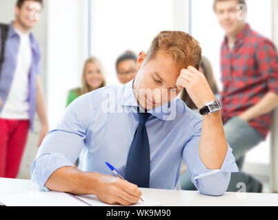 handsome teacher writing in notebook Stock Photo