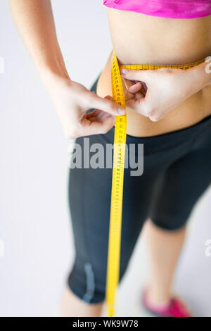 sport and diet concept - trained belly with measuring tape Stock Photo