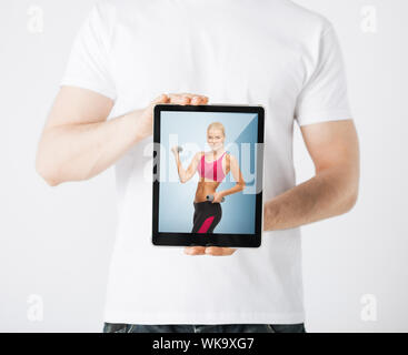 sport concept - man holding tablet pc with picture of woman doing exercise Stock Photo