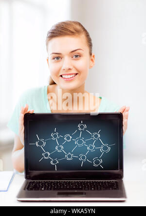 education, communication and internet concept - girl holding laptop with network contacts at school Stock Photo