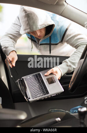 transportation, crime and ownership concept - thief stealing laptop from the car Stock Photo