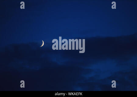 The moon showing against blue sky with clouds. Stock Photo