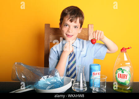 Extracting DNA from a Strawberry Science Experiment at Home with Young Boy doing strawberry DNA extraction experiment in School Uniform Stock Photo