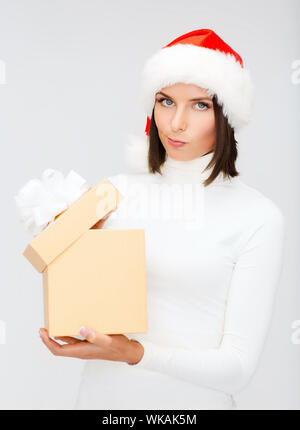 christmas, x-mas, winter, happiness concept - suspicious woman in santa helper hat with gift box Stock Photo