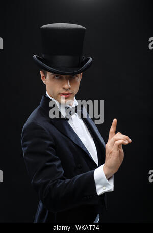 magic, performance, circus, show concept - magician in top hat showing trick Stock Photo