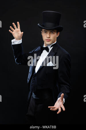 magic, performance, circus, show concept - magician in top hat showing trick Stock Photo