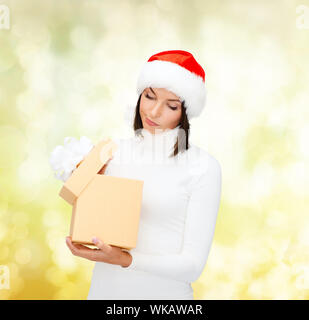 christmas, x-mas, winter, happiness concept - suspicious woman in santa helper hat with gift box Stock Photo