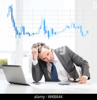 business, office and money concept - stressed businessman in black eyelgasses with laptop computer, papers, calculator and forex chart Stock Photo