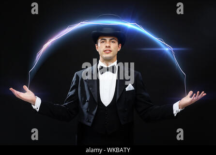 magic, performance, circus, show concept - magician in top hat showing trick Stock Photo