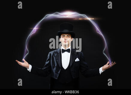 magic, performance, circus, show concept - magician in top hat showing trick Stock Photo