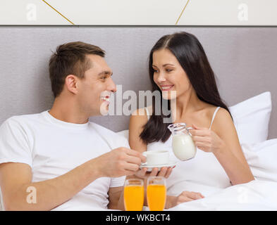 smiling couple having breakfast in bed in hotel Stock Photo