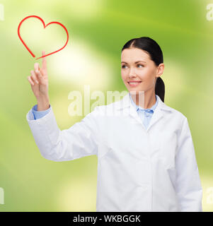 smiling female doctor pointing to heart Stock Photo