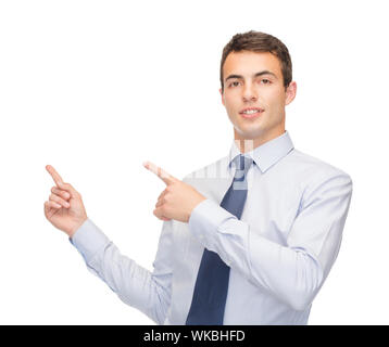 business and office, advertising, people concept - friendly young buisnessman pointing finger to something on virtual screen Stock Photo