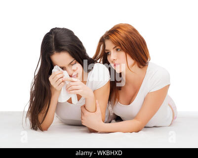 friendship and happy people concept - one teenage girl comforting another after break up Stock Photo