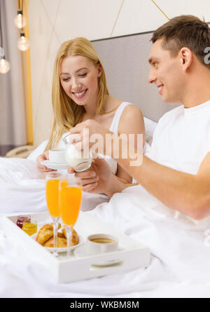 smiling couple having breakfast in bed in hotel Stock Photo