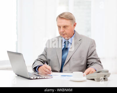 business, technologym communication and office concept - busy older businessman with laptop, charts, coffee and telephone in office Stock Photo