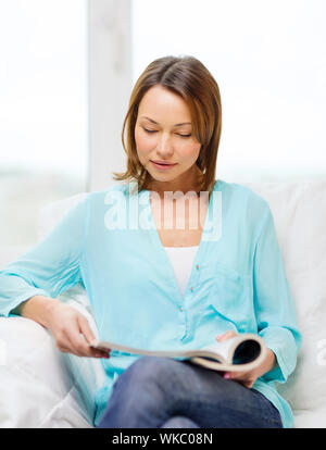 home and leasure concept - smiling woman reading magazine at home Stock Photo