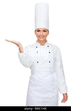 cooking, advertisement and food concept - smiling female chef holding something on palm of hand Stock Photo