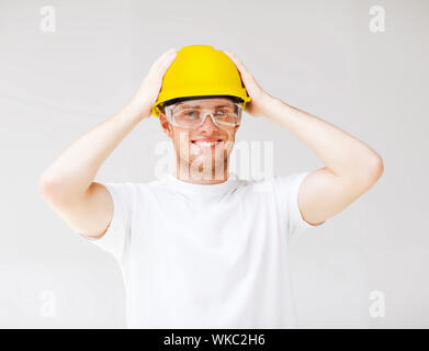 building, developing, consrtuction and architecture concept - picture of male builder in safety glasses and yellow helmet Stock Photo