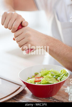 cooking and home concept - close up of male hands flavouring salad in a bowl Stock Photo