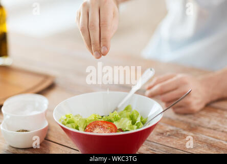 close up of male hands flavouring salad in a bowl Stock Photo