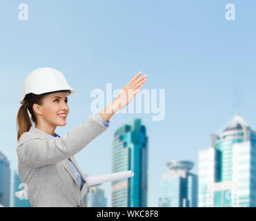 building, developing, consrtuction and architecture concept - friendly young smiling architect in white helmet with blueprints Stock Photo