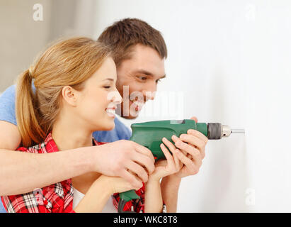 smiling couple drilling hole in wall at home Stock Photo