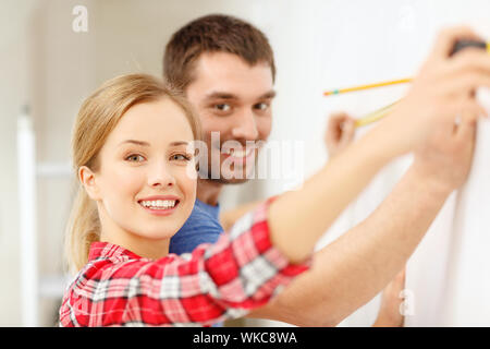 smiling couple measuring wall Stock Photo