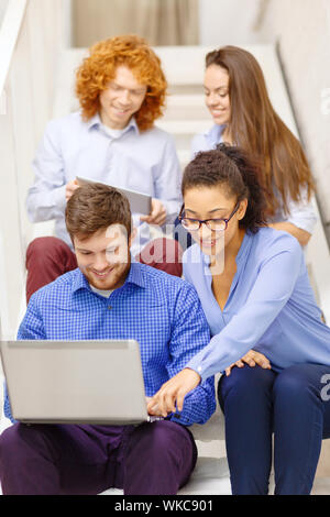 team with laptop and tablet pc on staircase Stock Photo