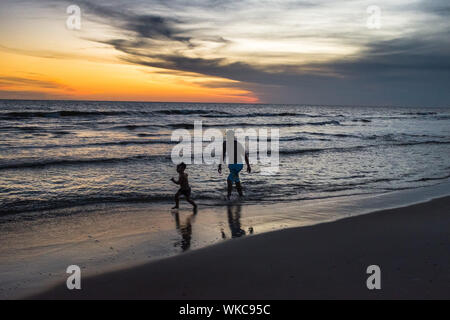 Uruguay: Uruguay, La Floresta, small city and resort on the Costa de Oro (Golden Coast). At dusk, a young father and his son are running in the waves, Stock Photo