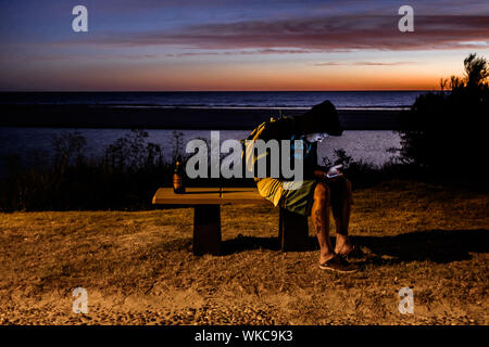 Uruguay: Uruguay, La Floresta, small city and resort on the Costa de Oro (Golden Coast). At dusk, a young boy is seated on a bench, facing the Rio de Stock Photo