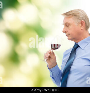 alcohol and beverage concept - elderly man smelling red wine Stock Photo