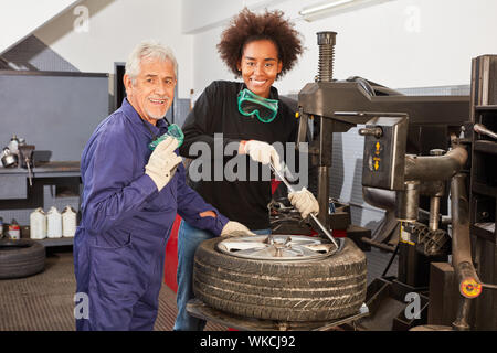 African apprentice and master in tire dressing in auto repair shop Stock Photo