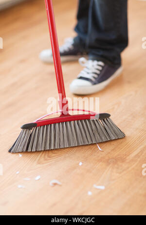 cleaning and home concept - close up of male brooming wooden floor Stock Photo